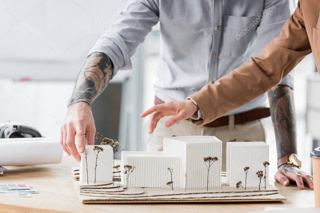 cropped view of virtual reality architects pointing with finger at model of house 