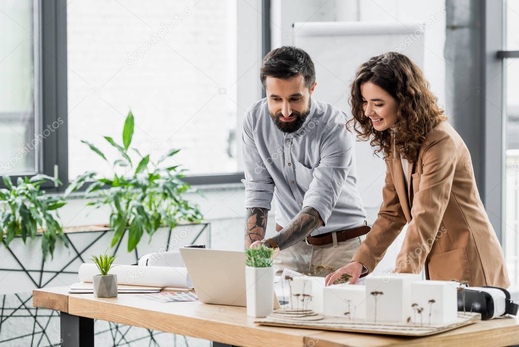 smiling virtual reality architects looking at laptop in office 