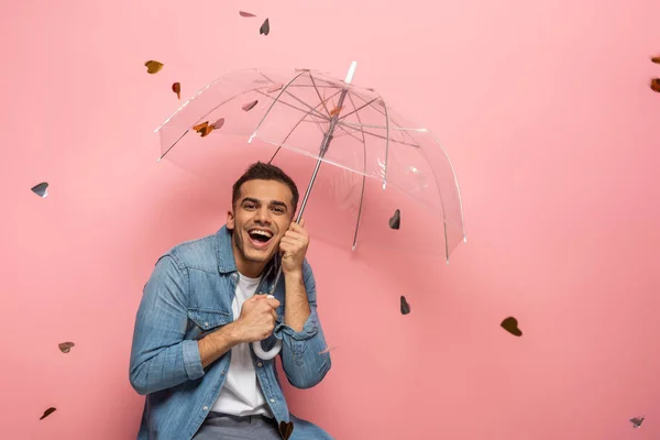 Cheerful Man Holding Umbrella Falling Heart Shaped Confetti Pink Background — Stock Photo, Image