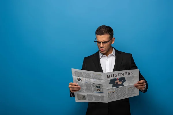 青い背景の新聞を読んでいる思慮深い実業家 — ストック写真