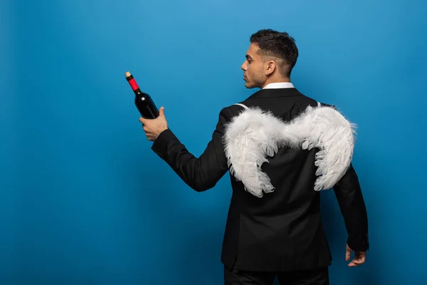 Back View Businessman White Wings Holding Bottle Wine Blue Background — Stock Photo, Image