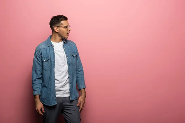 Side view of shocked man looking away on pink background