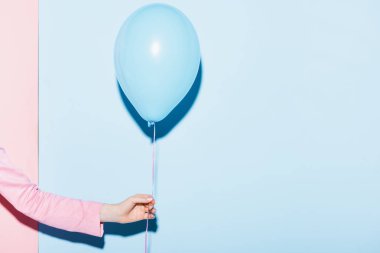 cropped view of woman holding balloon on pink and blue background  clipart
