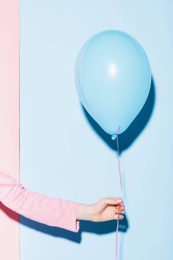 Kesilmiş pembe ve mavi arka planda balon tutan kadın görüntüsü 