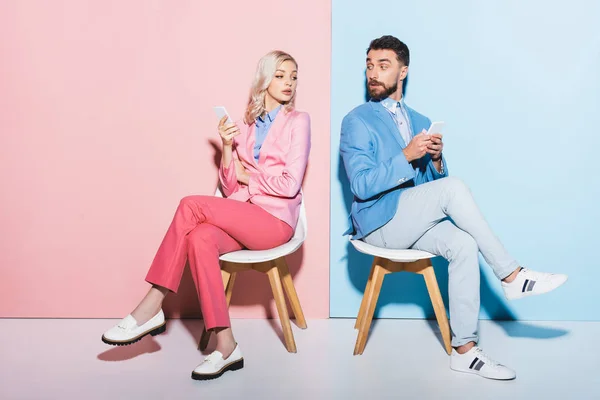 Mujer Sospechosa Hombre Guapo Sosteniendo Teléfonos Inteligentes Sobre Fondo Rosa — Foto de Stock