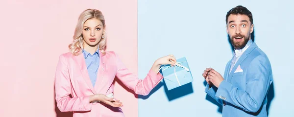 Панорамний Знімок Шокованої Жінки Тримає Подарунок Красивого Чоловіка Рожевому Синьому — стокове фото
