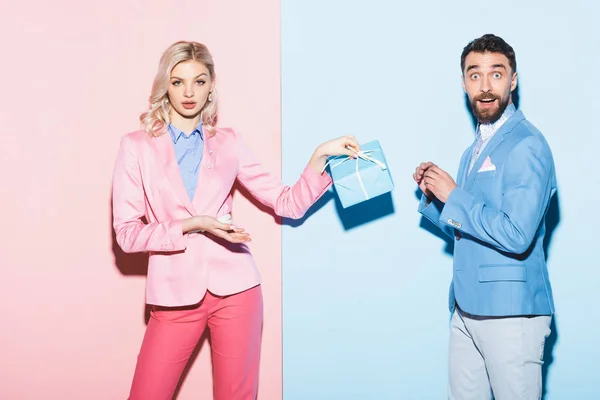 Mujer Conmocionada Sosteniendo Regalo Hombre Guapo Sobre Fondo Rosa Azul — Foto de Stock