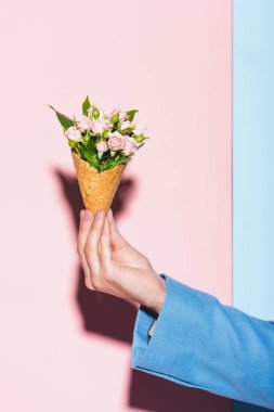 Pembe ve mavi arka planda elinde buket tutan adamın kırpılmış görüntüsü 