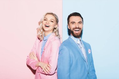 Çekici kadın ve yakışıklı adam pembe ve mavi arka planda kameraya gülümsüyor. 