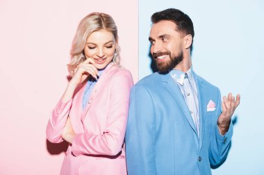 Çekici kadın ve yakışıklı erkek pembe ve mavi arka planda gülümsüyor. 