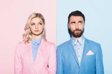 Hayalci kadın ve yakışıklı adam pembe ve mavi arka planda başka tarafa bakıyor. 