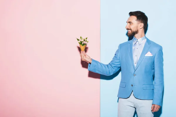 Lächelnder Mann Mit Blumenstrauß Auf Rosa Und Blauem Hintergrund — Stockfoto