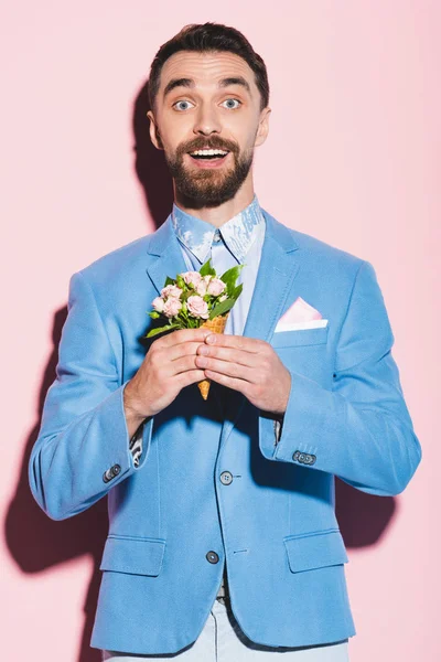 被震惊的男人拿着粉红色和蓝色背景的花束 — 图库照片