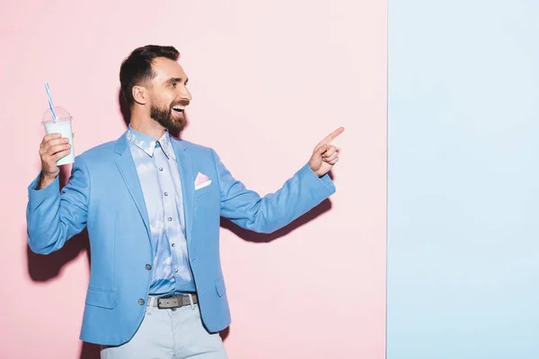 Homem Sorrindo Segurando Coquetel Apontando Com Dedo Fundo Rosa Azul — Fotografia de Stock