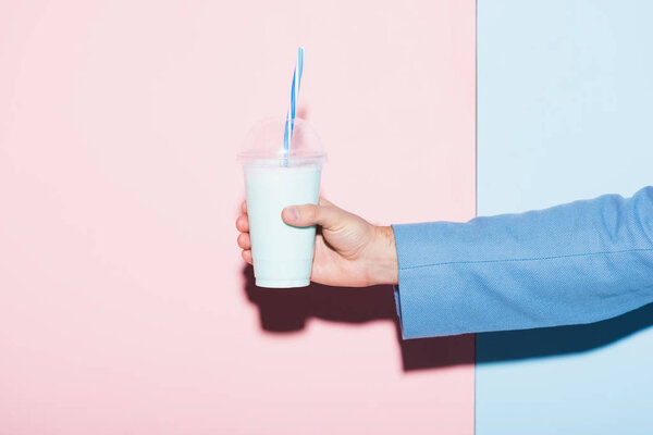 cropped view of man holding cocktail on pink and blue background 