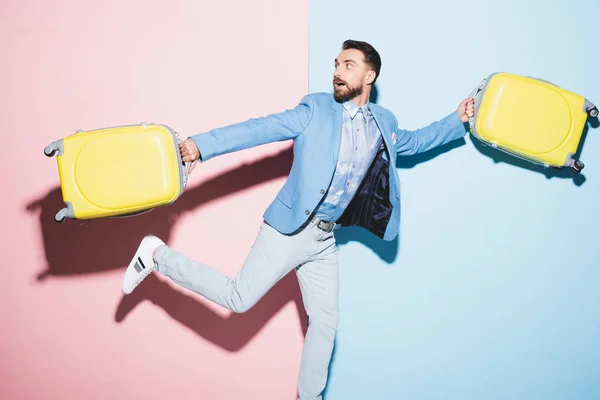 Hombre Sorprendido Sosteniendo Bolsas Viaje Sobre Fondo Rosa Azul — Foto de Stock