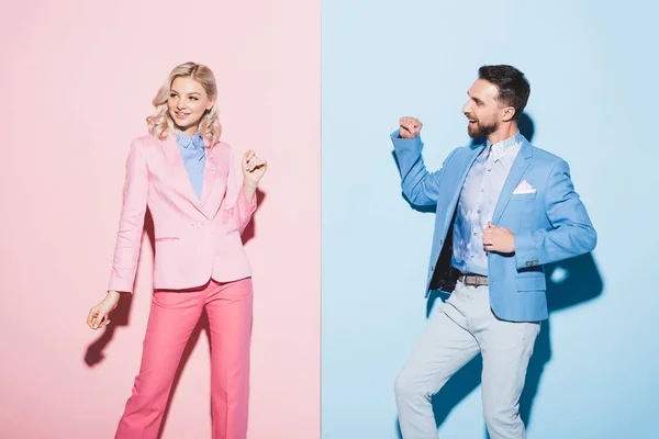 笑着的女人和英俊的男人在粉色和蓝色背景上做着肯定的手势 — 图库照片