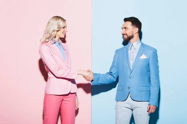 Glimlachende Vrouw Knappe Man Schudden Handen Roze Blauwe Achtergrond — Stockfoto