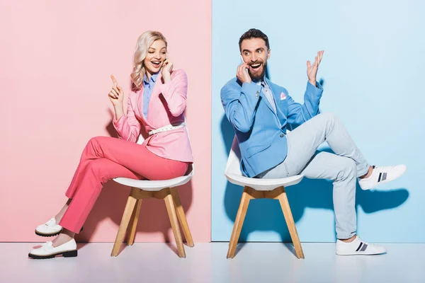 笑着的女人和英俊的男人在智能手机上用粉色和蓝色相间的背景说话 — 图库照片