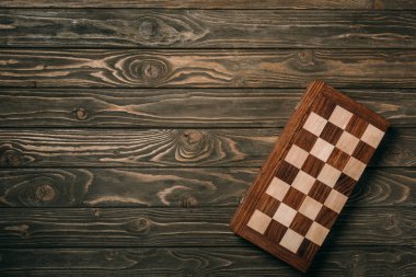 Top view of checkerboard on textured wooden background clipart