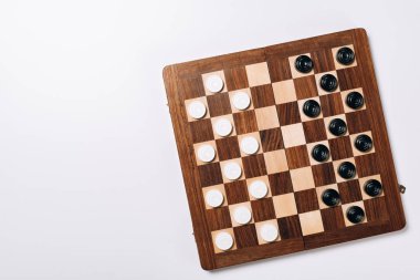 Top view of black and white checkers on wooden chessboard on white background clipart