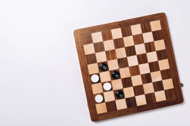 Top view of checkers on wooden checkerboard on white background clipart