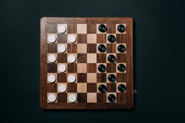 Siyah üzerine izole edilmiş tahta dama tahtası üzerindeki dama tahtalarının üst görünümü