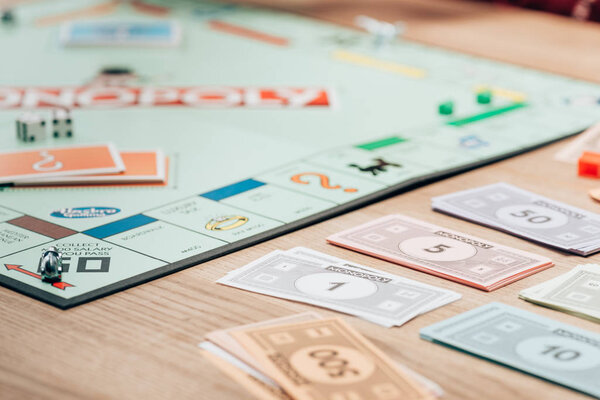 KYIV, UKRAINE - NOVEMBER 15, 2019: Selective focus of toy currency and monopoly game on wooden table