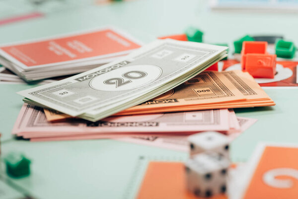 KYIV, UKRAINE - NOVEMBER 15, 2019: Selective focus of toy currency, figures and dices on monopoly game