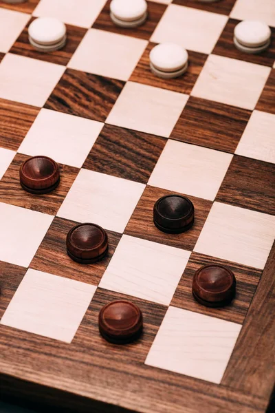 High angle view of checkers on wooden checkerboard