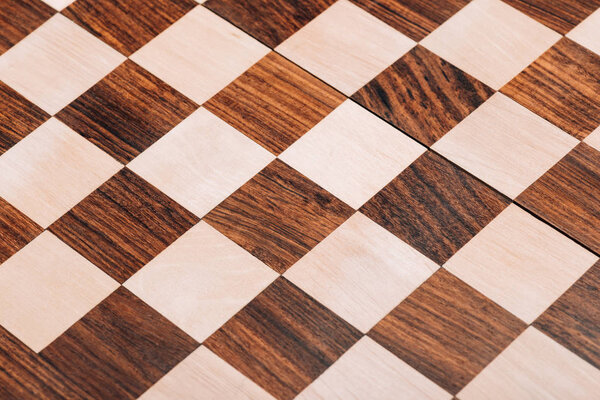 Surface of folding wooden checkerboard with brown and white squares
