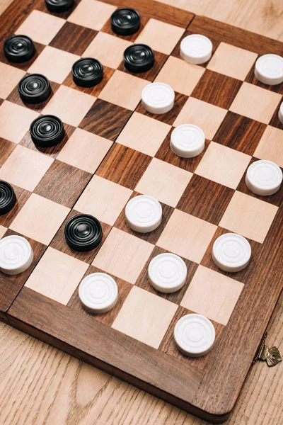 High angle view of checkers on checkerboard on wooden table