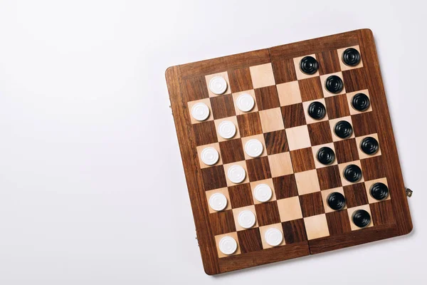 白色背景的木制棋盘上黑白格子的顶部视图 — 图库照片