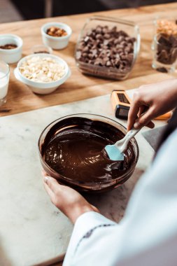 Çikolatayı kaseye karıştırırken silikon spatula tutmanın seçici odağı 