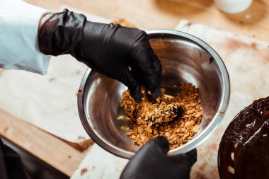 Siyah lateks eldivenli çikolatanın en üst görüntüsü. Lezzetli şekerlerin yanında taneli eldiven tutuyor. 