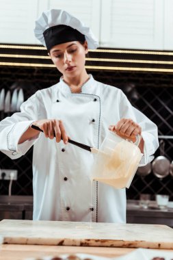 Erimiş beyaz çikolatanın yanında silikon spatula tutan çekici bir çikolata. 