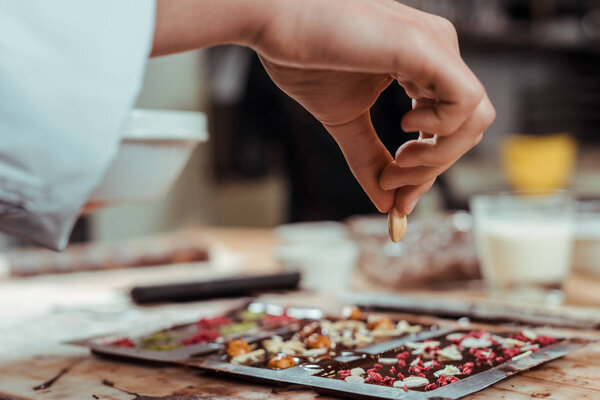 selective focus of chocolatier holding nut dark chocolate bar 