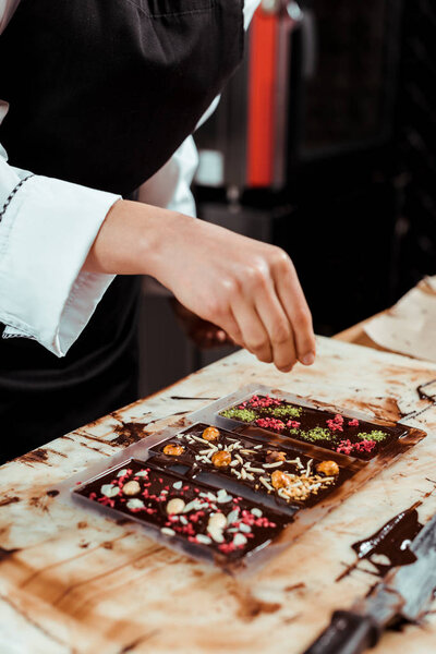 cropped view of chocolatier near dark chocolate bars 