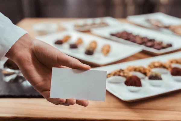 Cropped View Chocolatier Holding Blank Card Tasty Chocolate Candies — Stock Photo, Image