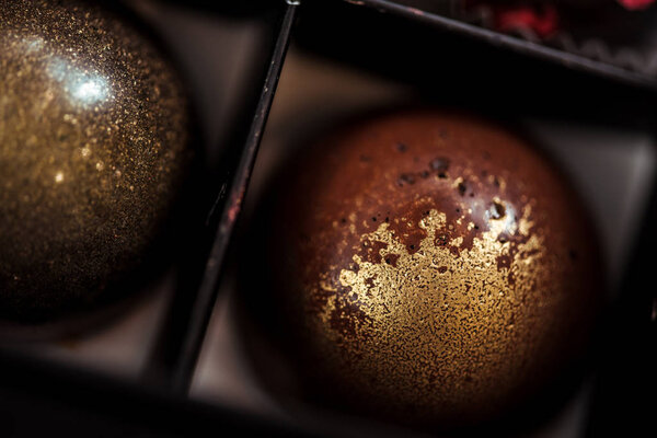close up of sweet chocolate balls with golden powder in box