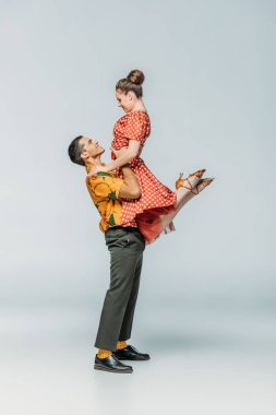 Gri arkaplanda dans ederken dans eden yakışıklı dansçının yan görünüşü