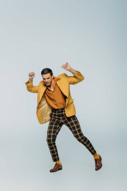 Yakışıklı, şık dansçı gri arka planda dans ediyor.