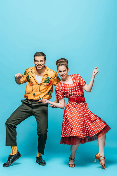 веселые танцоры смотрят в камеру, танцуя буги-вуги на синем фоне
