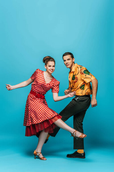 веселые танцоры смотрят в камеру, танцуя буги-вуги на синем фоне
