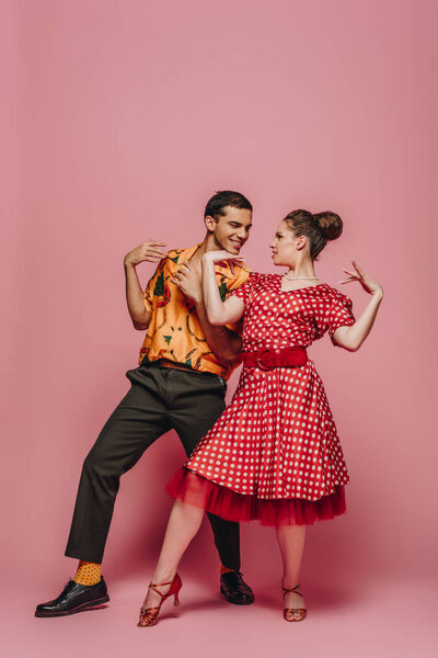 элегантные танцоры смотрят друг на друга, танцуя буги-вуги на розовом фоне
