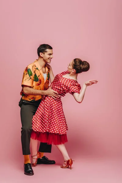 在粉色背景下跳舞时 时髦的舞者相互凝视着对方 — 图库照片
