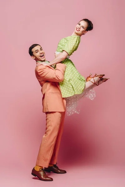 ピンクの背景でブギウギを踊りながら女の子を保持するスタイリッシュなダンサー — ストック写真