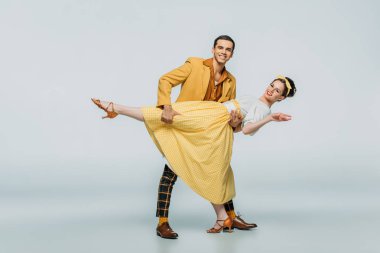 Gri arka planda boogie-woogie dans ederken yakışıklı dansçı yardımcı partner