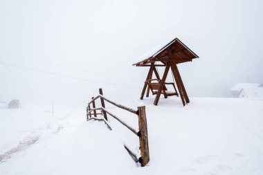 Tahta çit ve sis içindeki karlı dağ köyünde salıncak.