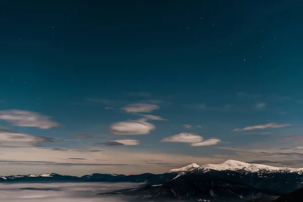 Akşamları Beyaz Kabarık Bulutlu Karlı Dağların Manzarası — Stok fotoğraf